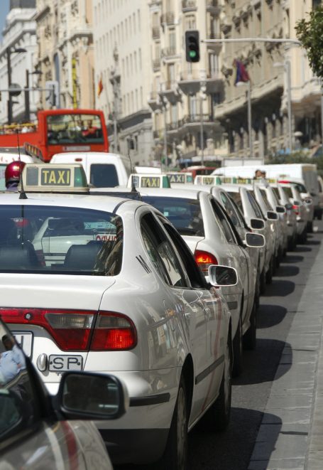 Ligne de taxis blancs attendant à un feu rouge en ville.