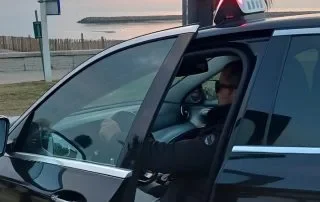 Conducteur dans une voiture noire, vue au crépuscule près de l'eau.