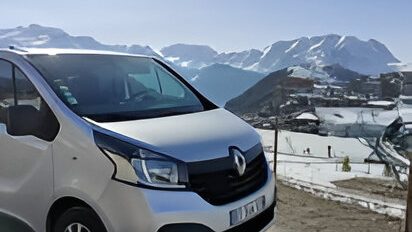 Un fourgon Renault avec des montagnes enneigées en arrière-plan.