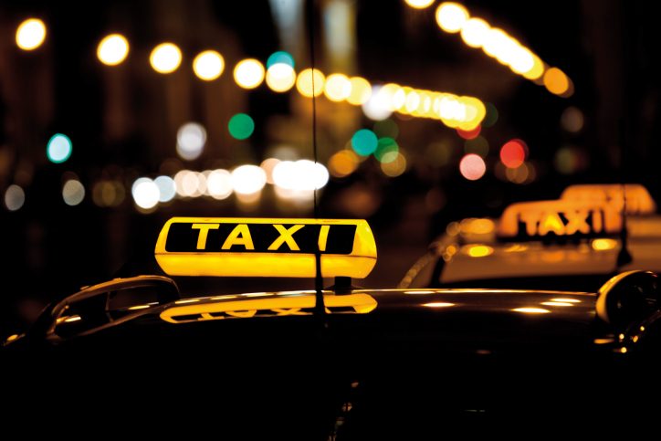 Taxis illuminés la nuit avec des lumières floues en arrière-plan.