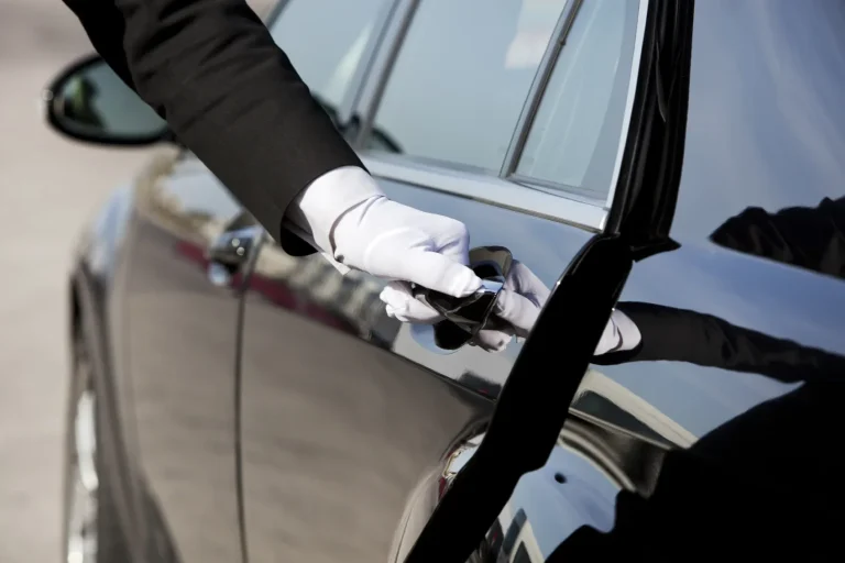 Main en gants blancs ouvrant la porte d'une voiture noire.