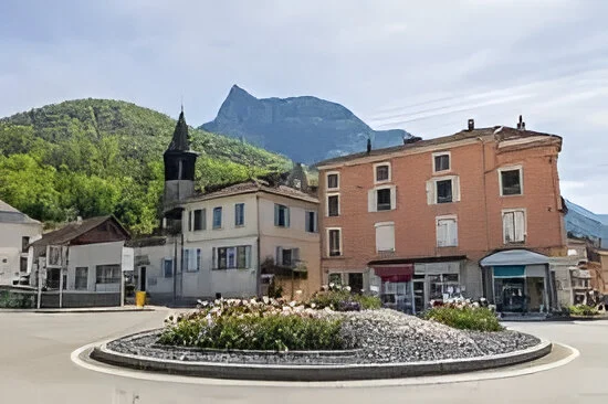 Vue d'un village alpin avec église et montagnes en arrière-plan.