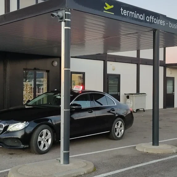 taxi mercedes noir aeroport de grenoble saint-geoirs taxi mercedes noir stationné devant un bâtiment de terminal d'affaires.