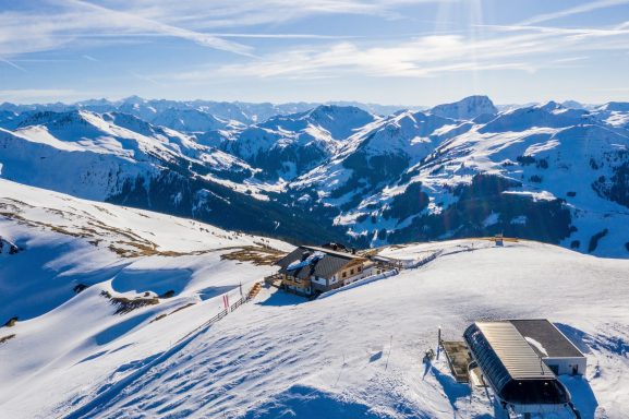 Vue panoramique des montagnes enneigées sous un ciel bleu clair, avec des pistes de ski.